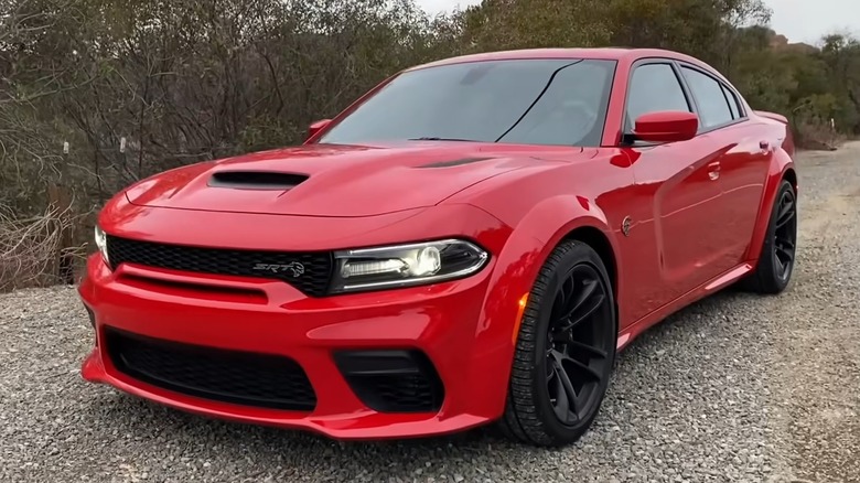 A red Dodge Charger Hellcat parked on a road.