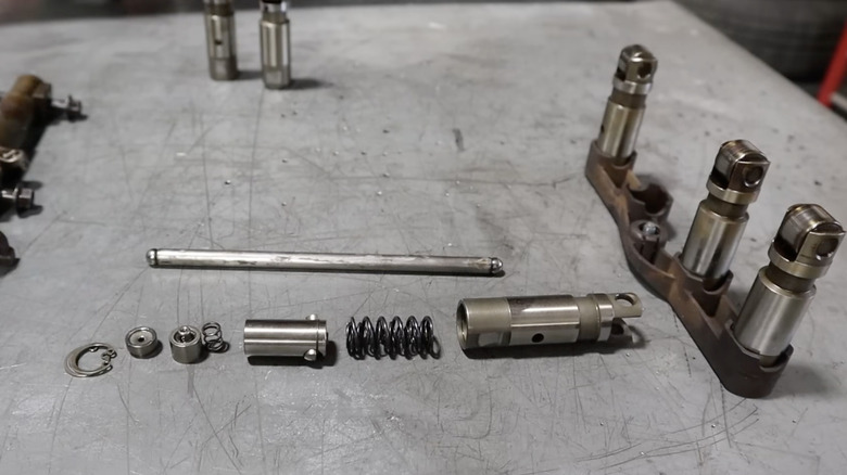 Disassembled HEMI roller lifter parts arranged on a workshop table.