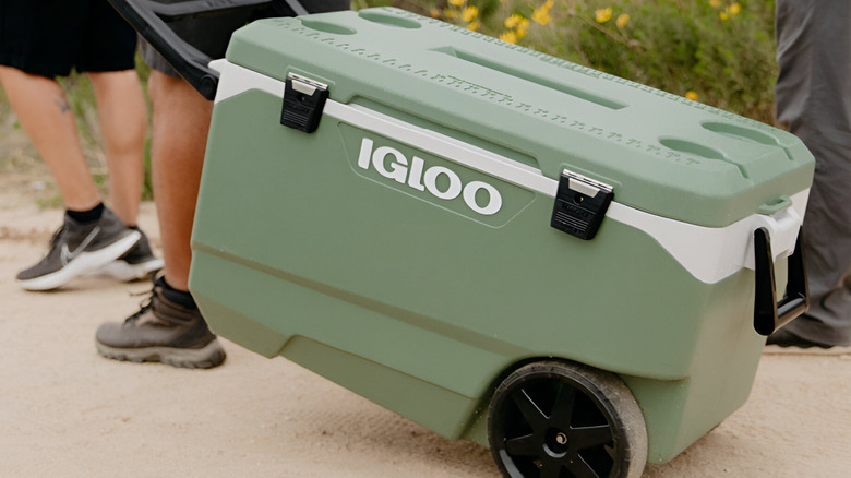 A group of people towing an Igloo 90-Quart Flip & Tow Rolling Cooler