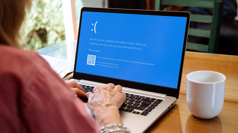 Person using laptop showing Blue screen of death or BSOD