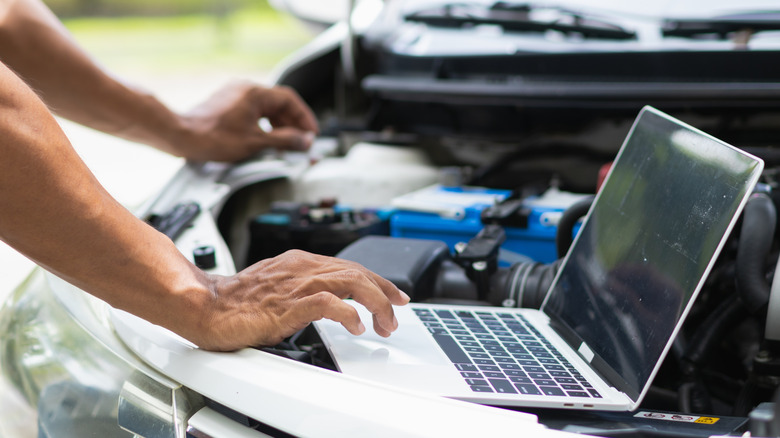 Man pulling car data from vehicle on laptop