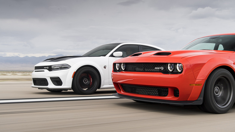 2021 Dodge Charger SRT and Dodge Challenger SRT driving side-by-side down airport runway, front-left view