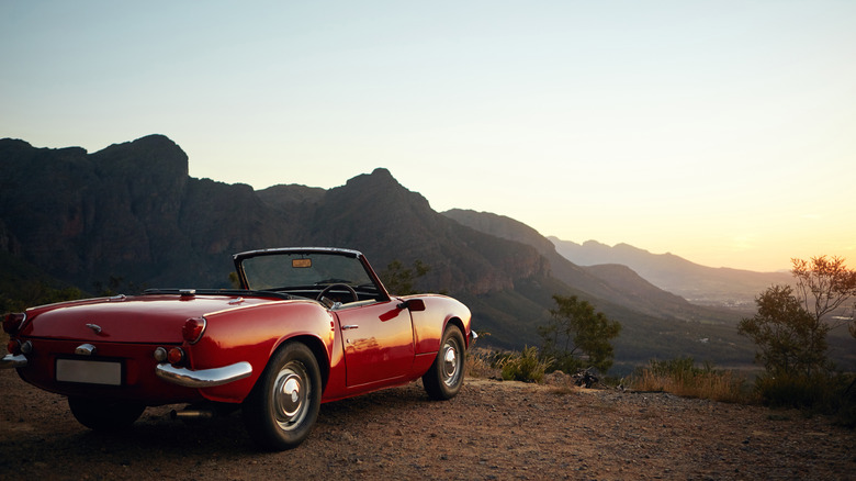 A red Triumph Spitfire parked in the mountains at sunset