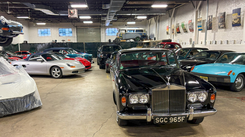 A car collection parked indoors with a Rolls Royce Silver Shadow in the foreground