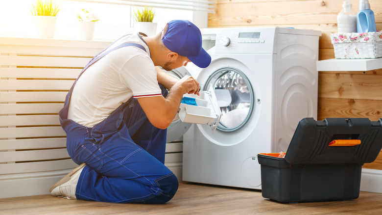 A person repairing a washing machine.
