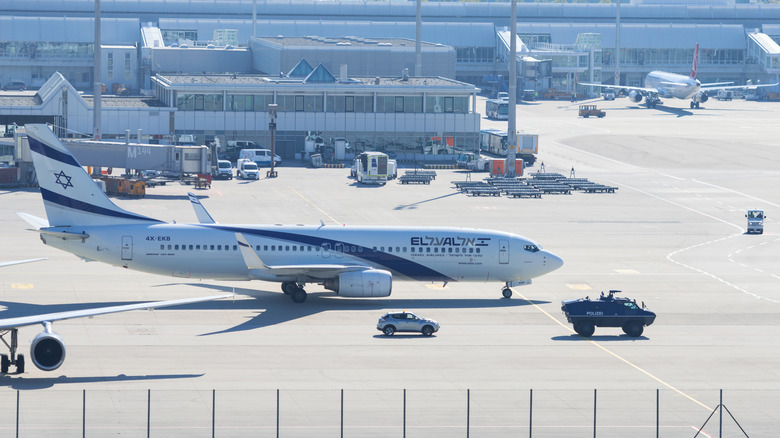 Armed police armored vehicle near Israeli El-Al airliner