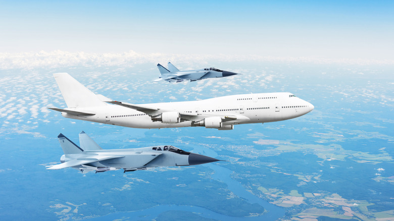 Large passenger plane, accompanied by two military fighters