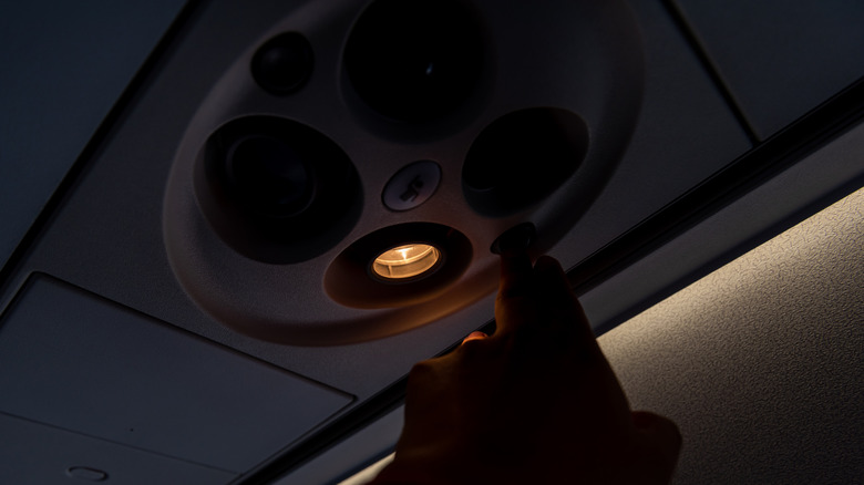 Person turning on overhead reading lights on plane