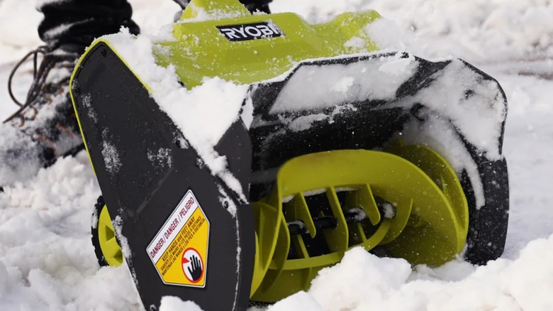 The head of a Ryobi snow shovel in heavy snow.