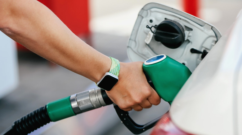 Man pumping gas into open fuel door