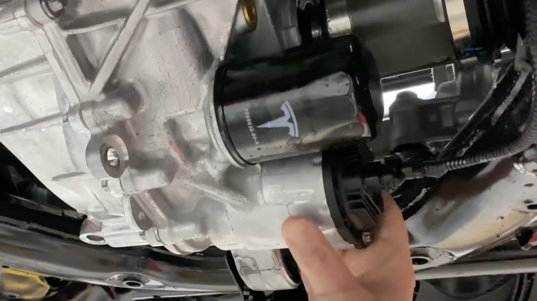 hand reaching for mounted Tesla gearbox oil filter