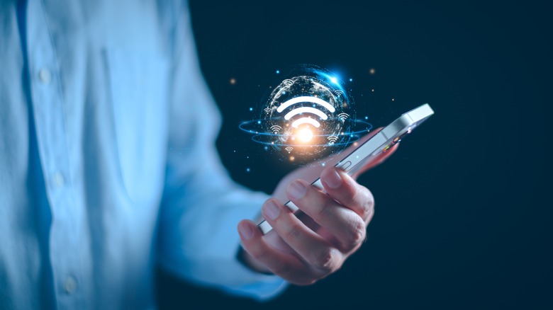 Person holding a phone with a floating WIFI graphic in a bubble