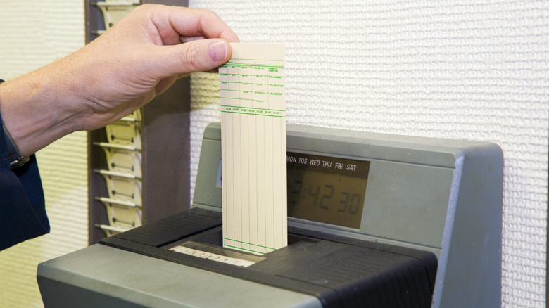 A worker is punching his time card with the automatic clock