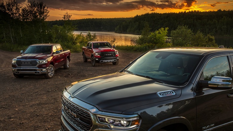 Three Ram trucks parked on grass in the evening