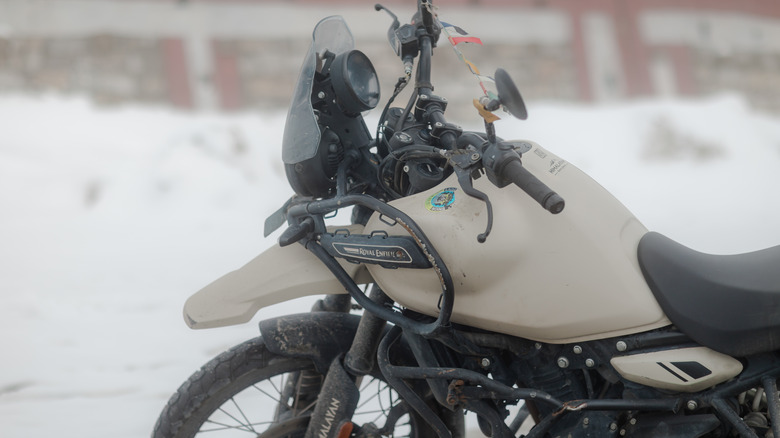 Dirt-covered adventure motorcycle parked in a snowy landscape,