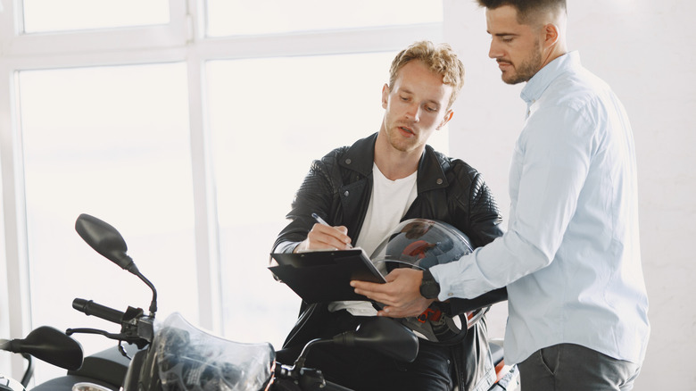 A man signing an agreement for purchasing a motorcycle