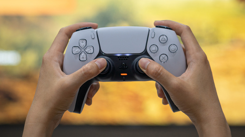 PS5 controller with blurred TV screen in background
