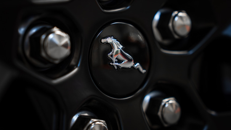 A close-up of a Ford Mustang wheel with chromed lug nuts.