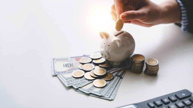 Woman saving money shown with cash and a piggy bank