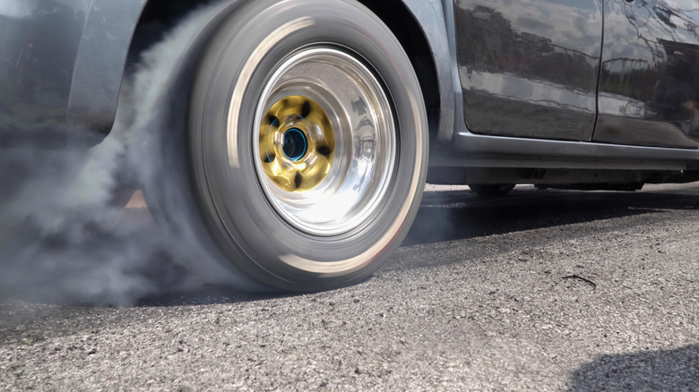 A black vehicle doing a burnout on rear tire