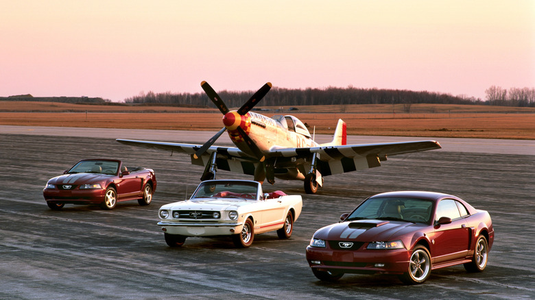 Three Ford Mustangs, 2004 Ford Mustang Anniversary Edition coupe and convertible with with 1965 Ford Mustang in-between, North American P-51 Mustang parked behind