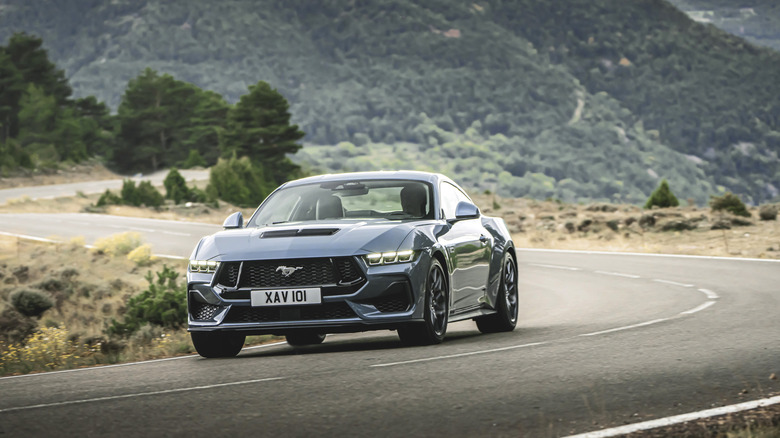 2025 Ford Mustang GT driving down mountain road, front-left view