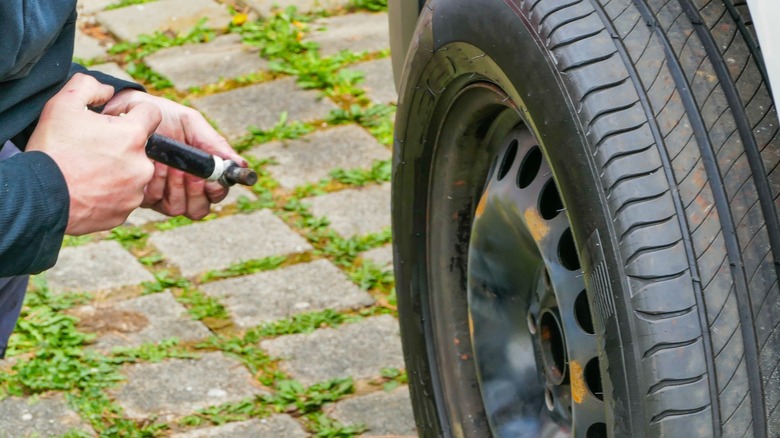 A mechanic greasing lug nuts before installing a car wheel.