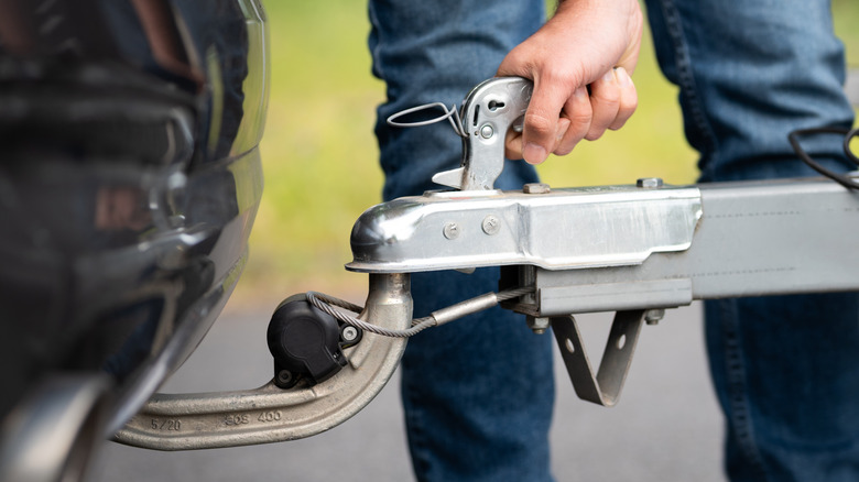 Man connecting trailer to tow hitch