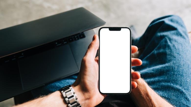 Person holding iPhone with white screen