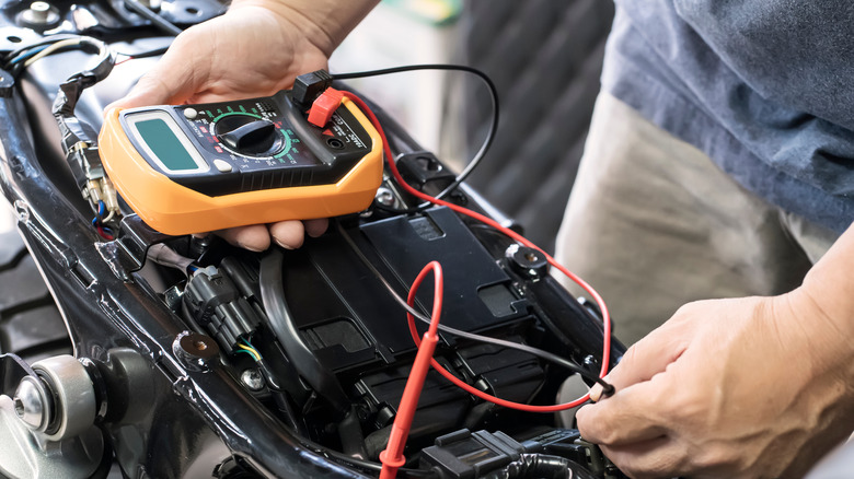 Man using multimeter to test motorcycle battery