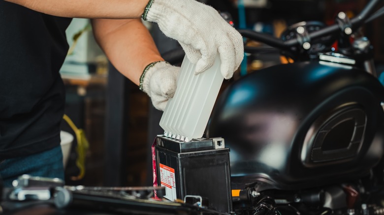 mechanic replaces motorcycle battery
