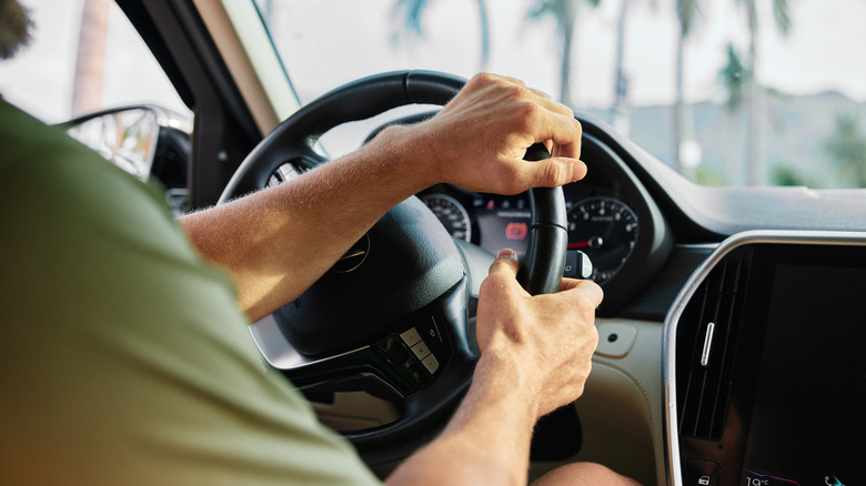 Two hands on a steering wheel.