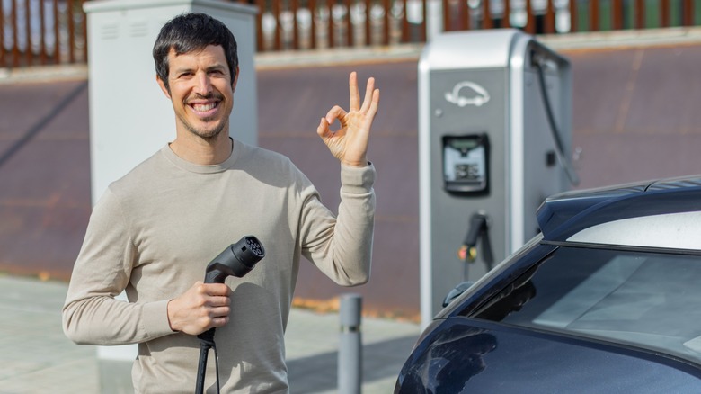 A smiling man holding an EV charger
