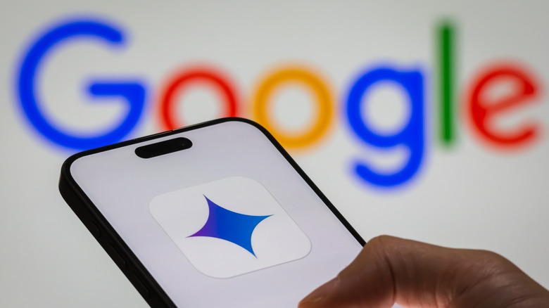 Close-up of a person's hand holding a smartphone displaying the logo of 