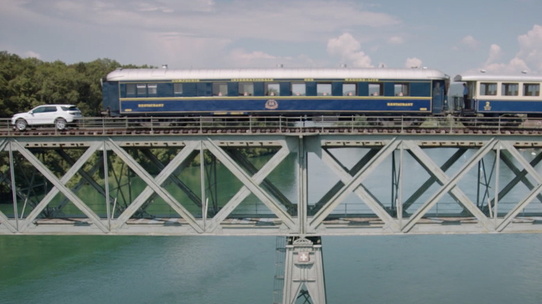 A side shot of the Land Rover Discovery Sport pulling a train across a bridge in Switzerland.