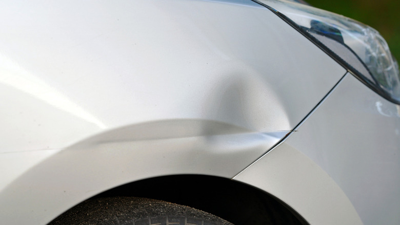 A white car fender with a dent in it