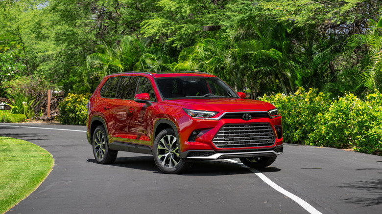 2025 Toyota Grand Highlander parked on a paved surface, front 3/4 view, Ruby Flare Pearl