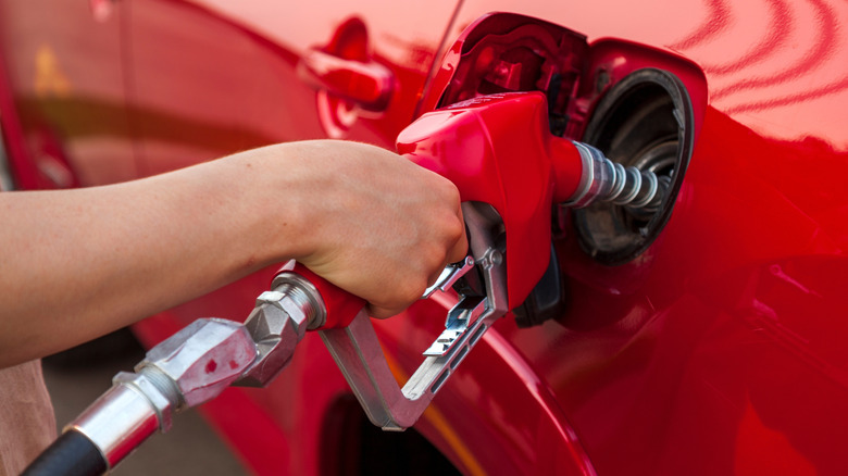 hand on gas pump during refueling of red car