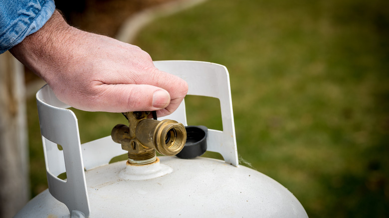 Propane tank valve being turned by hand