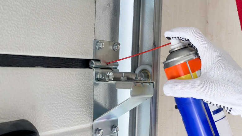 A worker lubricates sectional doors after installation in a garage