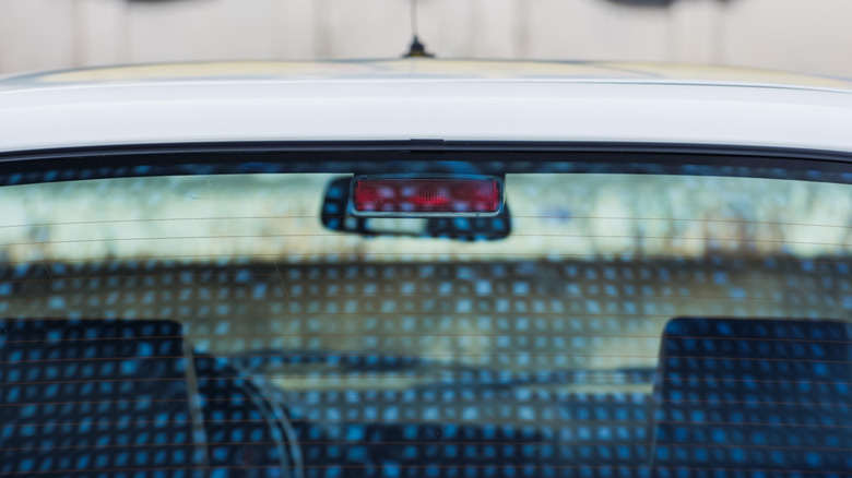 The Center High‑Mounted Stop Lamp behind the rear window of a white car.