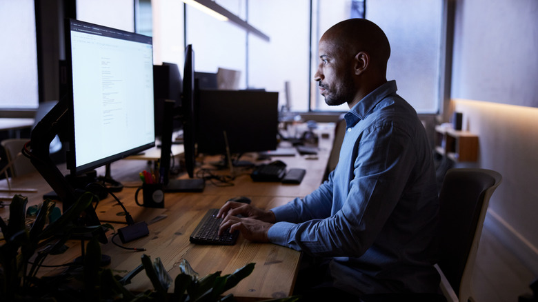 Man working on a computer with a bright monitor