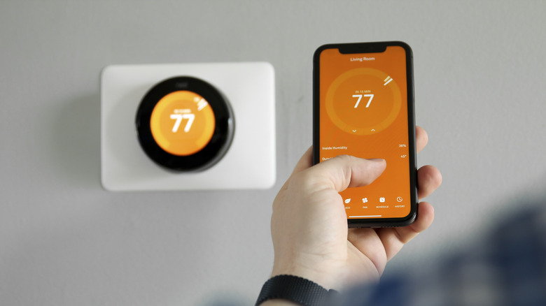 A Person Using A Smartphone App To Control A Smart Thermostat