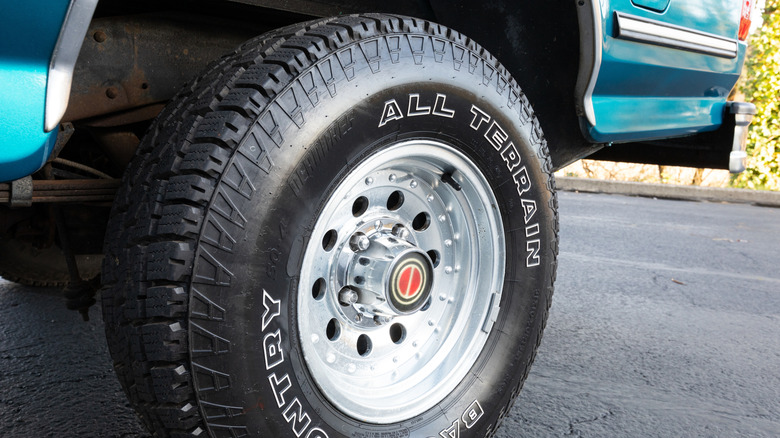 A close-up of a light blue pickup truck mounted with a back country all terrain tire.