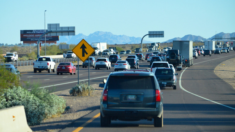 Merging lane sign ahead with slight traffic on the highway