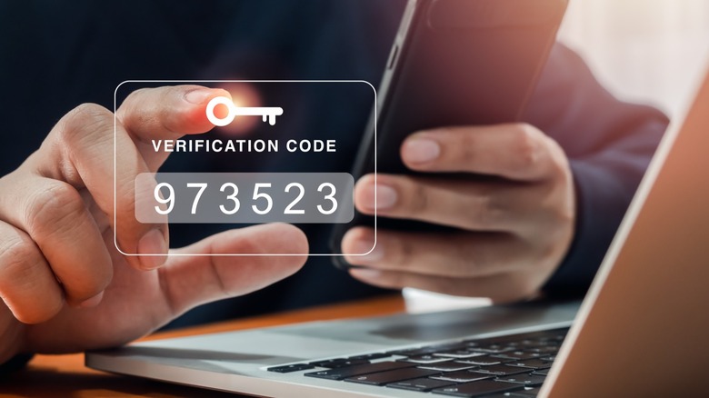 Image depicting two factor authentication with person holding phone in front of laptop