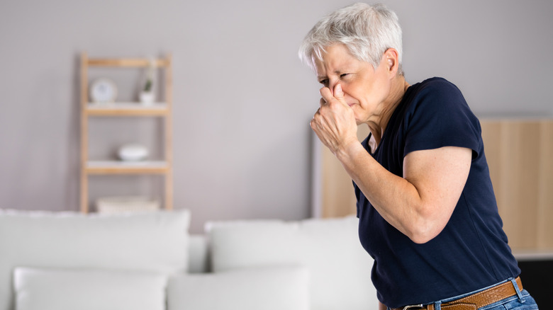 an old lady holding her nose because of a bad smell