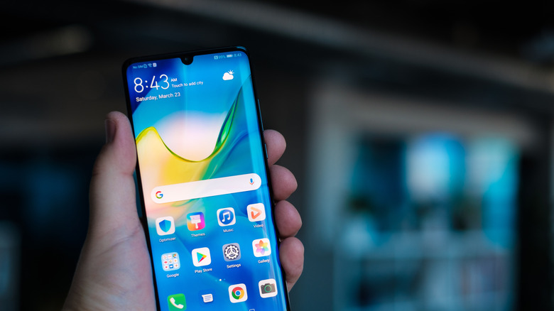 A person holding up a Huawei P30 Pro displaying the home screen