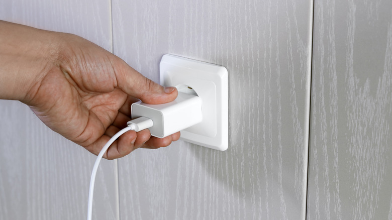 Person plugs charger into a wall socket.