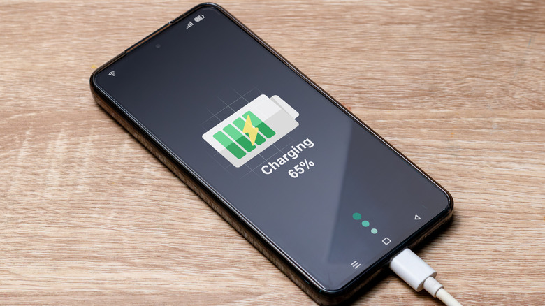 A smartphone on charge on a table.